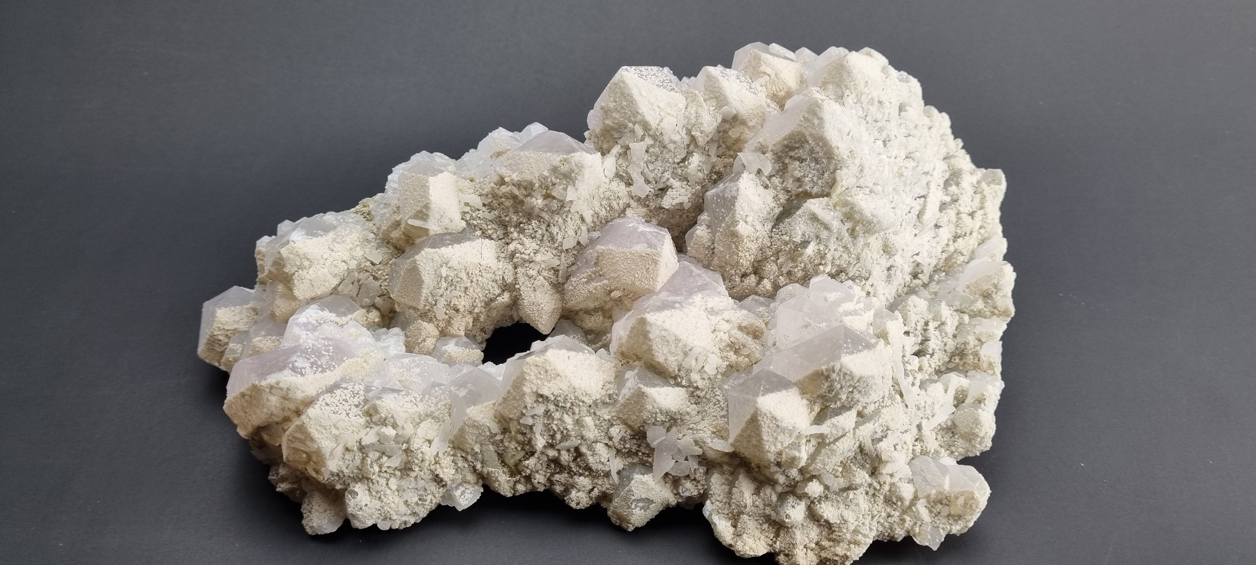 Quartz crystal cluster with a preferential dusting of Calcite and minor Pyrite on matrix